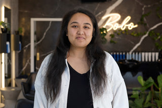 Woman standing in a modern interior setting with 'Bobo' neon sign