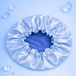 Blue satin hair bonnet on a light blue background with water droplets.