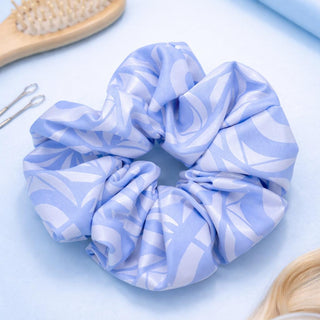 Blue and white patterned scrunchie with hair care products on a light blue background