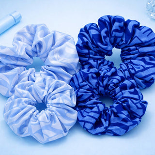 Three blue and white striped scrunchies on a light blue background